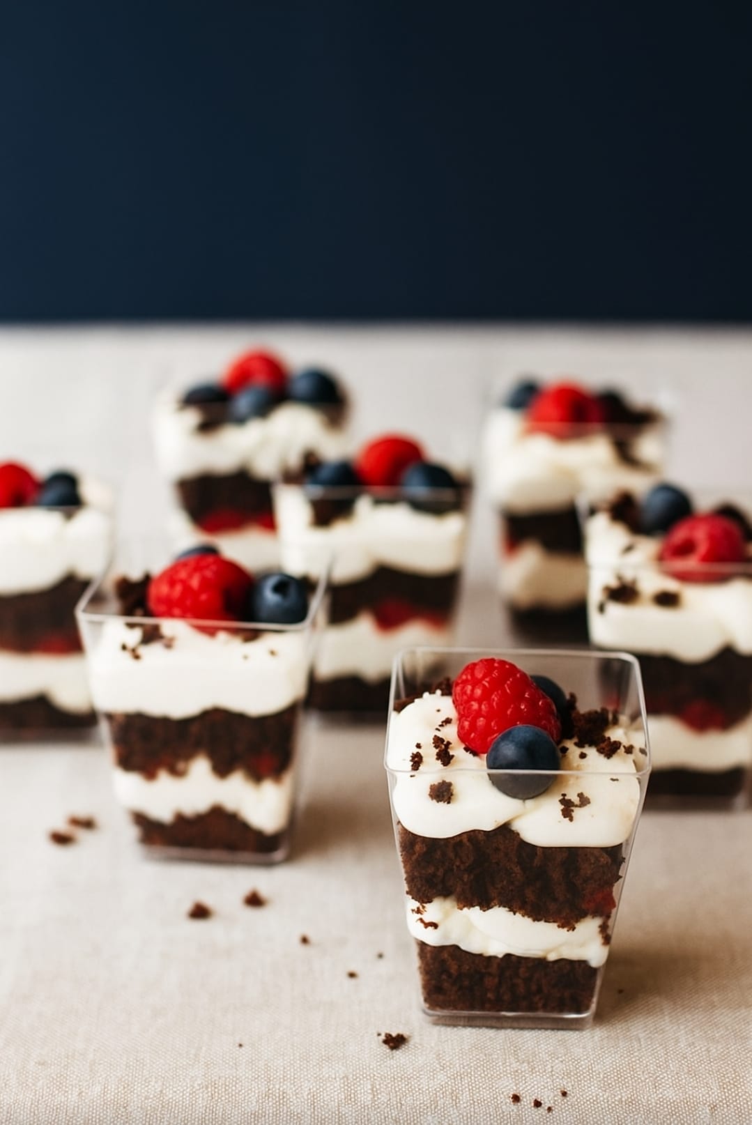 Postre al vaso con bizcocho de chocolate, crema de queso y frambuesas.